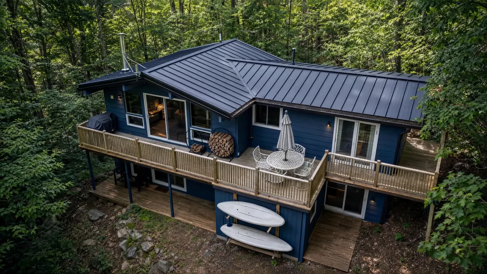 An Endura metal roof on a blue cottage surrounded by woodland