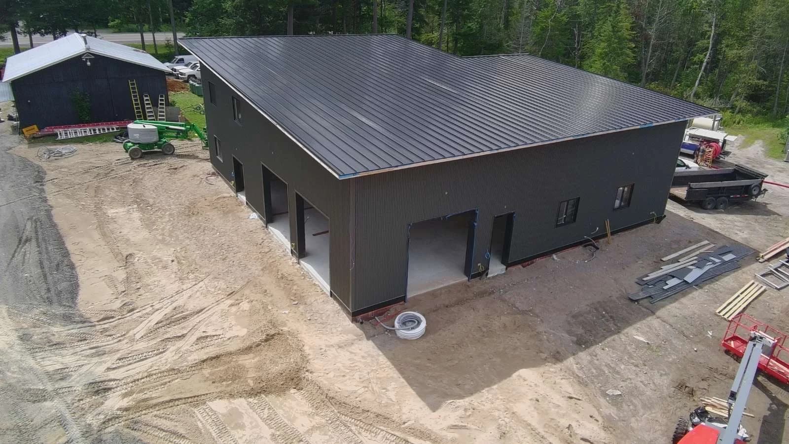 Aerial view of a dark standing seam roof above a garage and matching metal walls