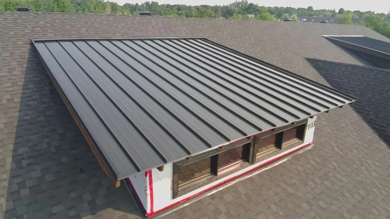 Standing seam roof on a raised dormer within a larger shingled roof