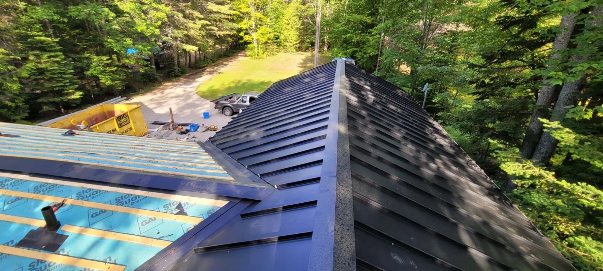 Standing seam roof installation showing finished panels and exposed supporting layers