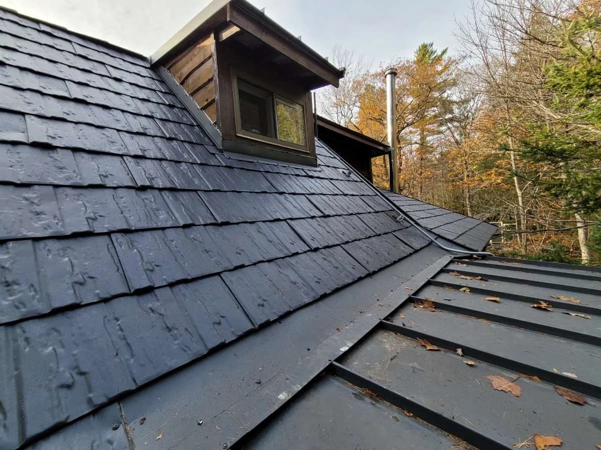 Metal shingle roof and dormer above a standing seam roof edge