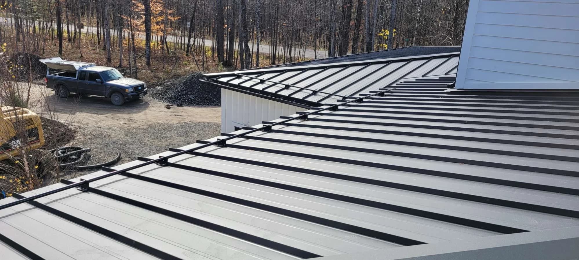 Standing seam roof with snow retention alongside a house