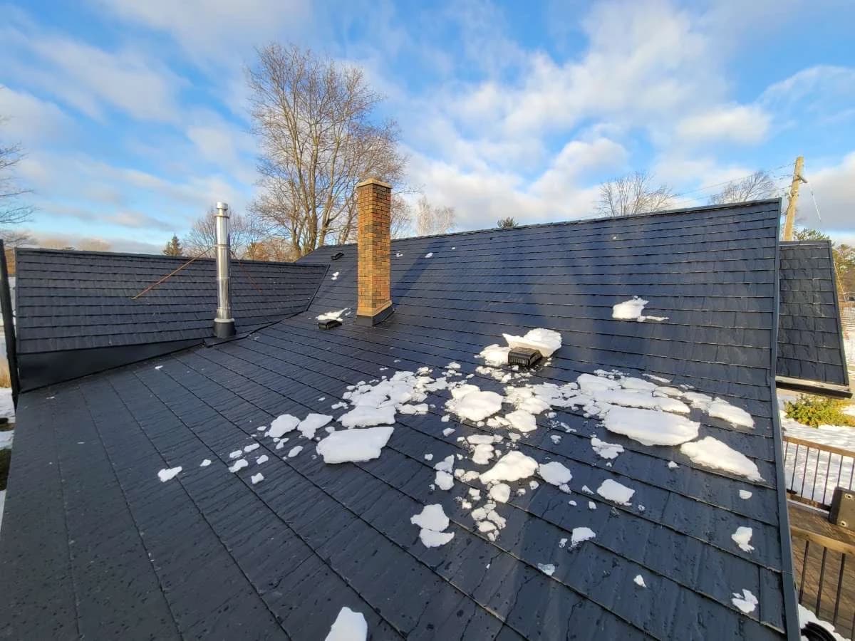 Metal shingle roof and chimney with patches of snow